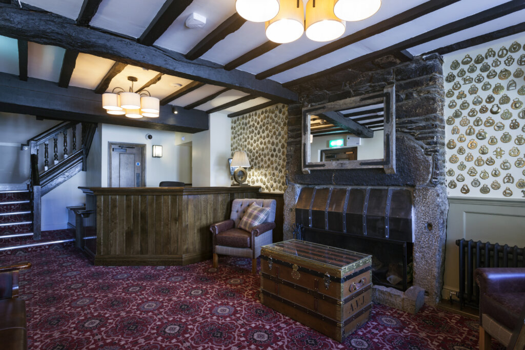 Room with black wooden beamed ceiling, armchair and trunk in The White Hart Hotel pub