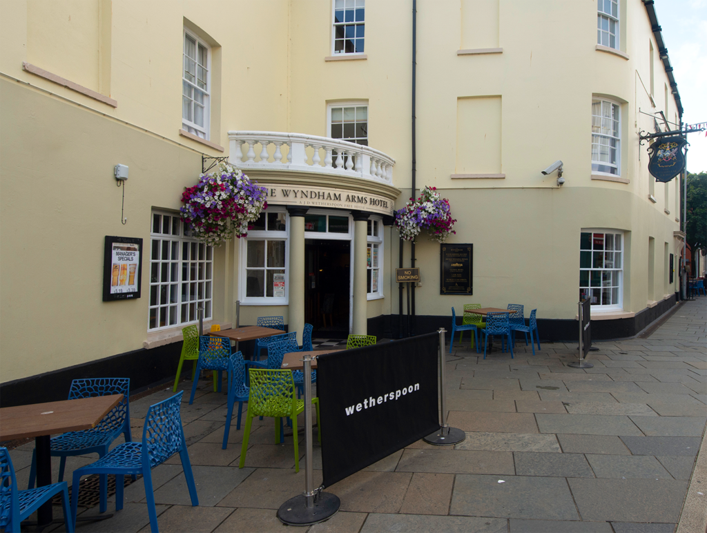 tables, chairs and hanging baskets outside The Wyndham Arms Hotel pub